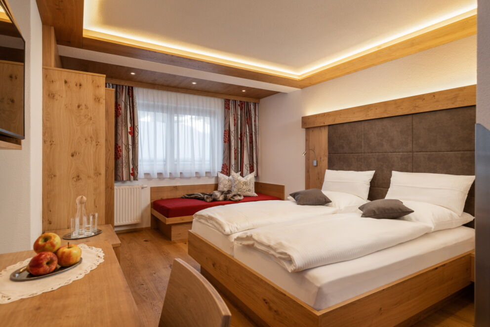Gemütliches Doppelbett mit relaxing-Couch und Balkon.