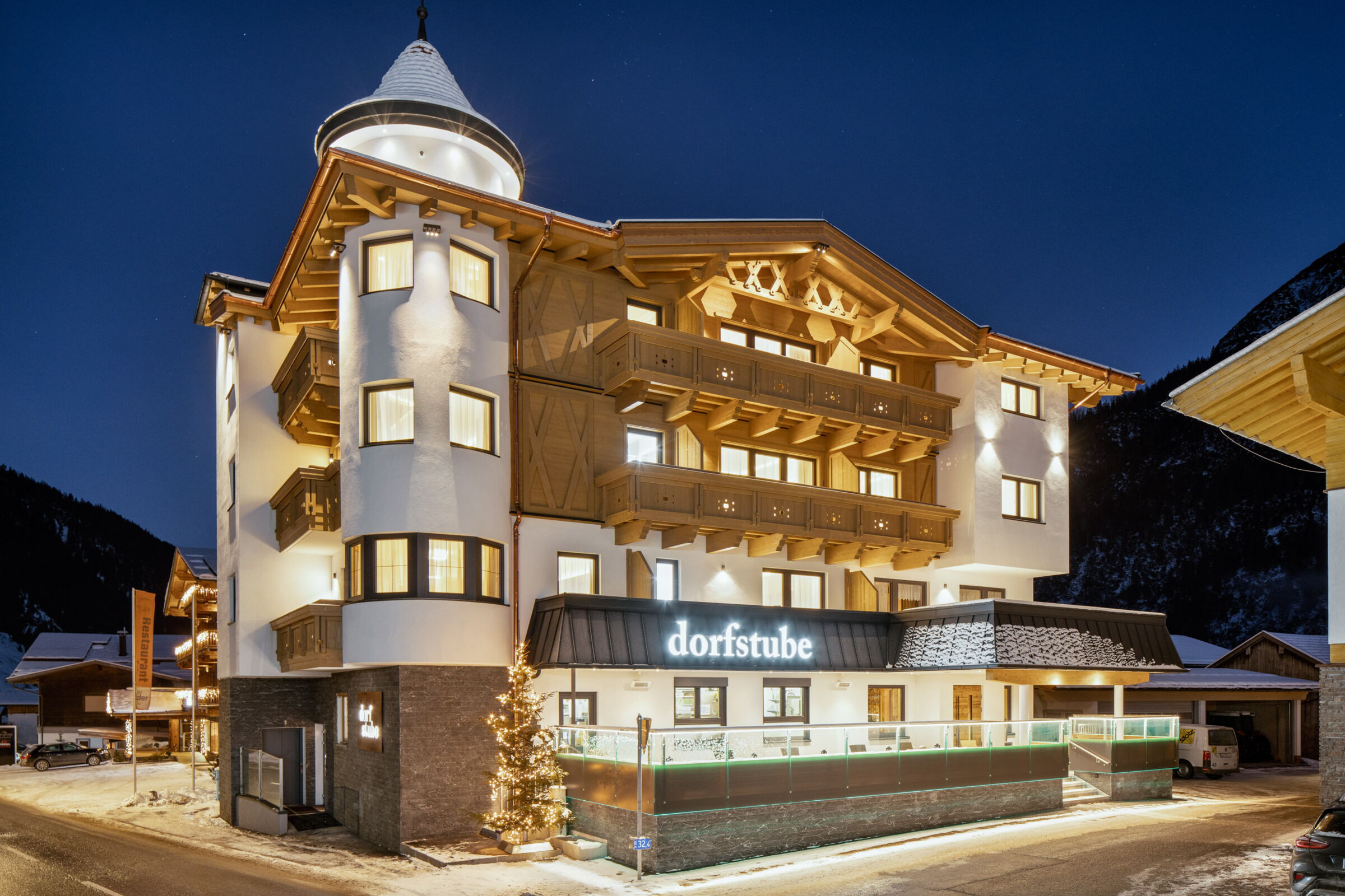 Die Außenansicht der beleuchteten Dorfstube Holzgau im Winter am Abend,
