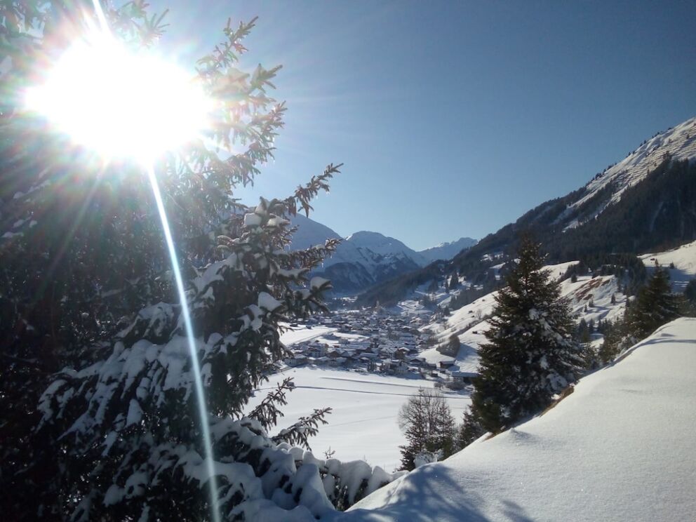 Winterlandschaft im oberen Lechtal bei Holzgau mit verschneiten Wiesen und Sonnenschein.