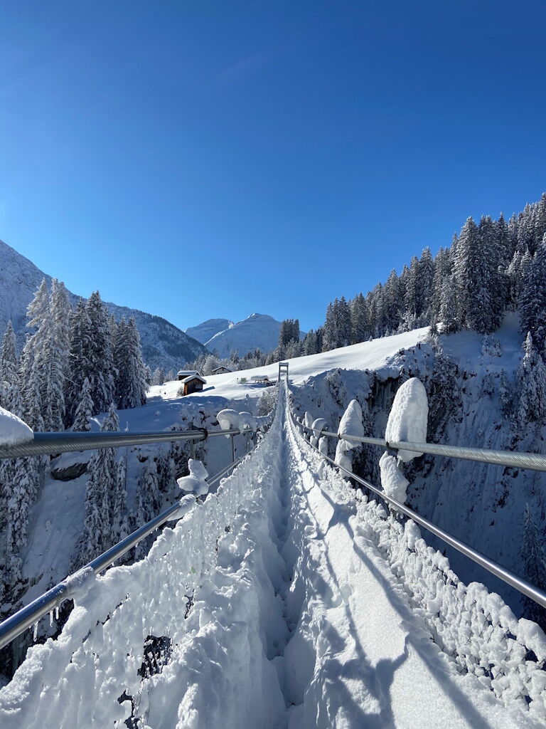 Winterwandern nach kräftigem Schneefall in Holzgau über die Hängebrücke.