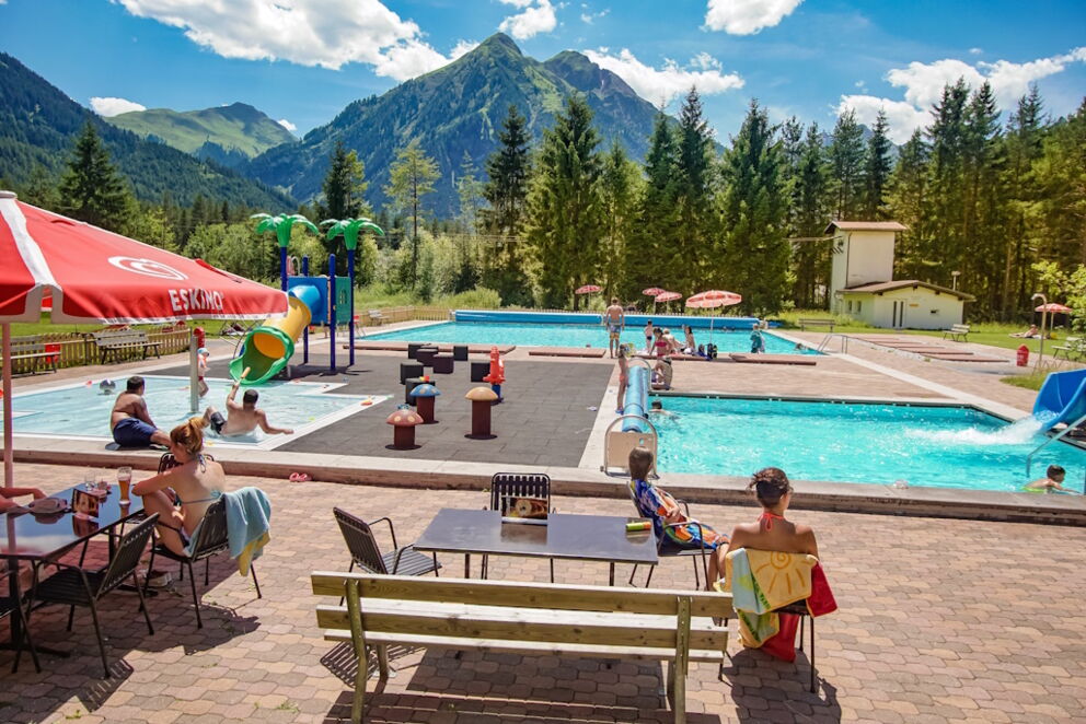 Freischwimmbad in Bach im Lechtal mit Becken und Rutsche und Schwimmbadbesuchern.