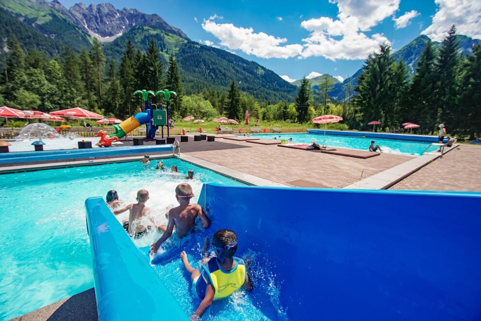 Kinder auf der Wasserrutsche im Freischwimmbad in Bach.