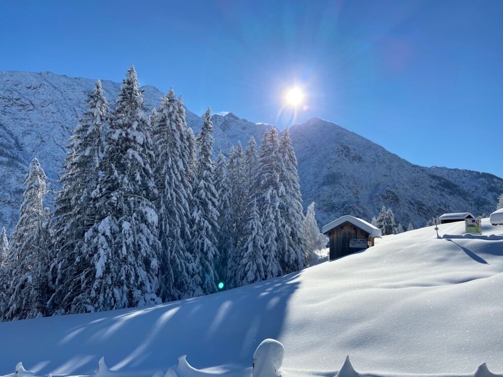 Tiefschnee stapfen bis zur Fußgängerhängebrücke in Holzgau bei verschneiter Landschaft.