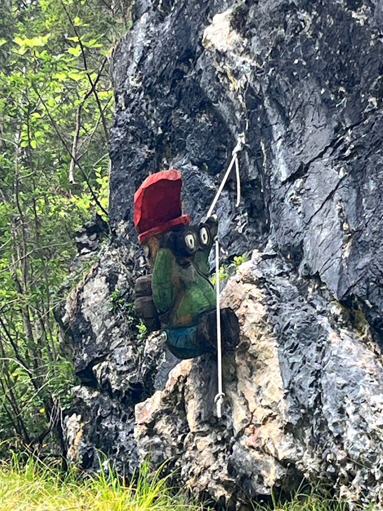 Abseilweltmeister ist unser Gipfel-Gnom mit Fernglas am Felsen in den Lechauen am Zaubermärchenwaldweg.