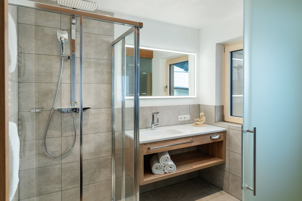 Geräumiges Badezimmer mit Tageslicht, Glasschiebetüre und Dusche.
