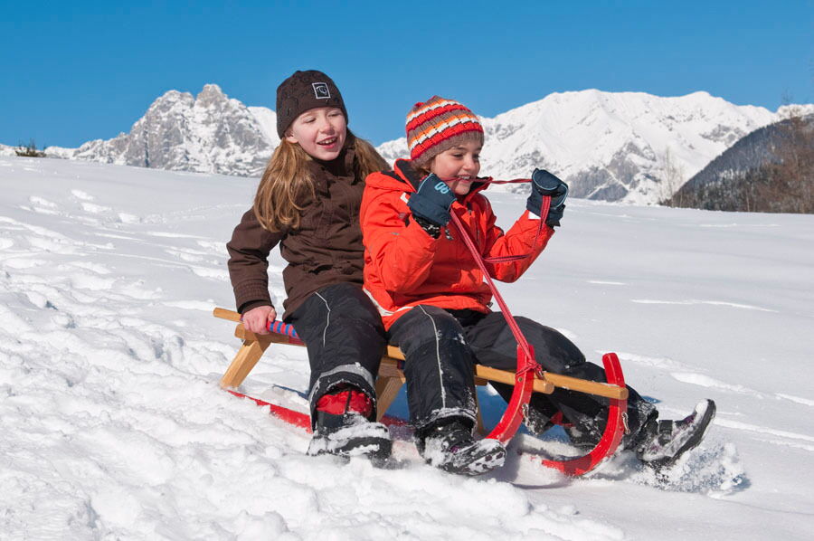 Spaß im Schnee haben die Kinder beim Rodeln.
