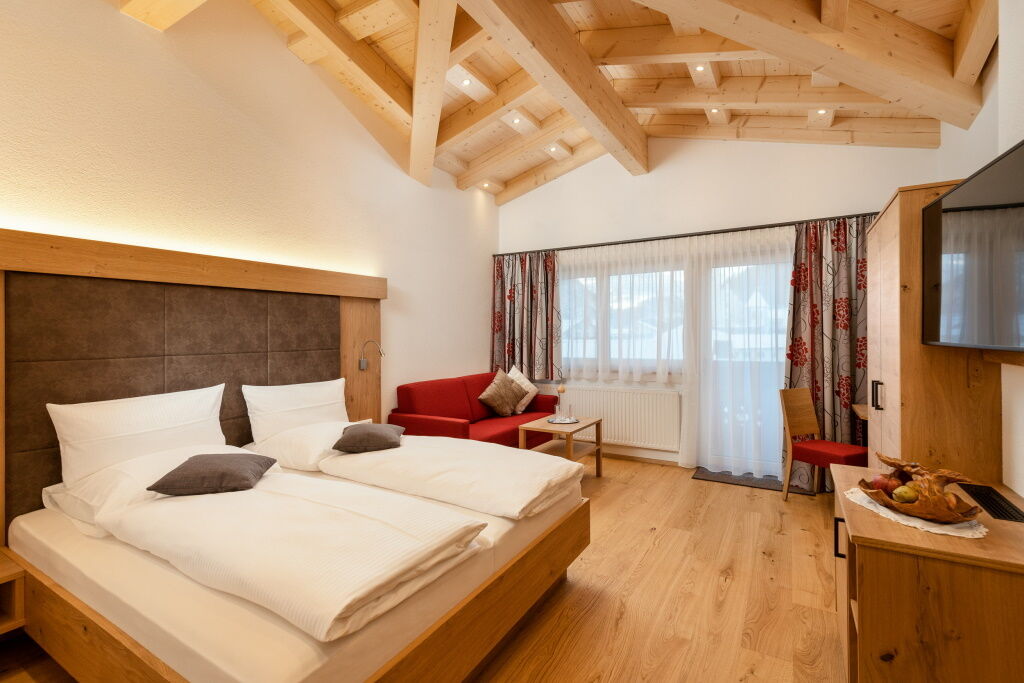 Großes Doppelbettzimmer mit breitem Balkon, Sichtdachstuhl und Abendsonne.