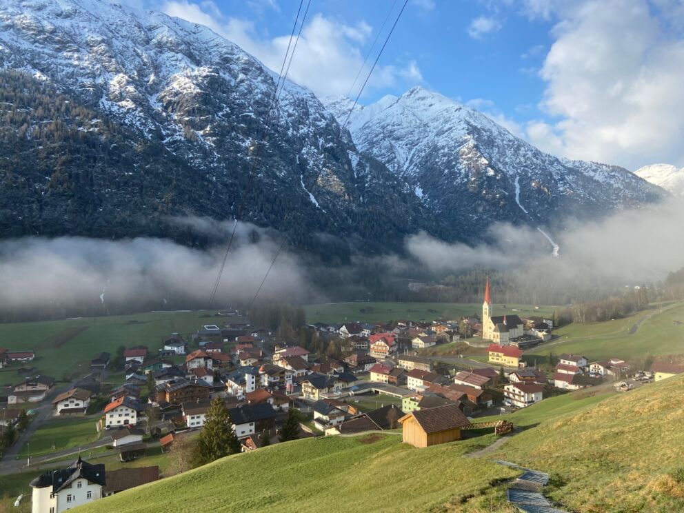 Der Tag erwacht im Lechtal in Holzgau. Wandern ab der Dorfstube, die Unterkunft in Holzgau. Holzau im Morgennebel, wandern am Vital-Weg zur Hängebrücke.
