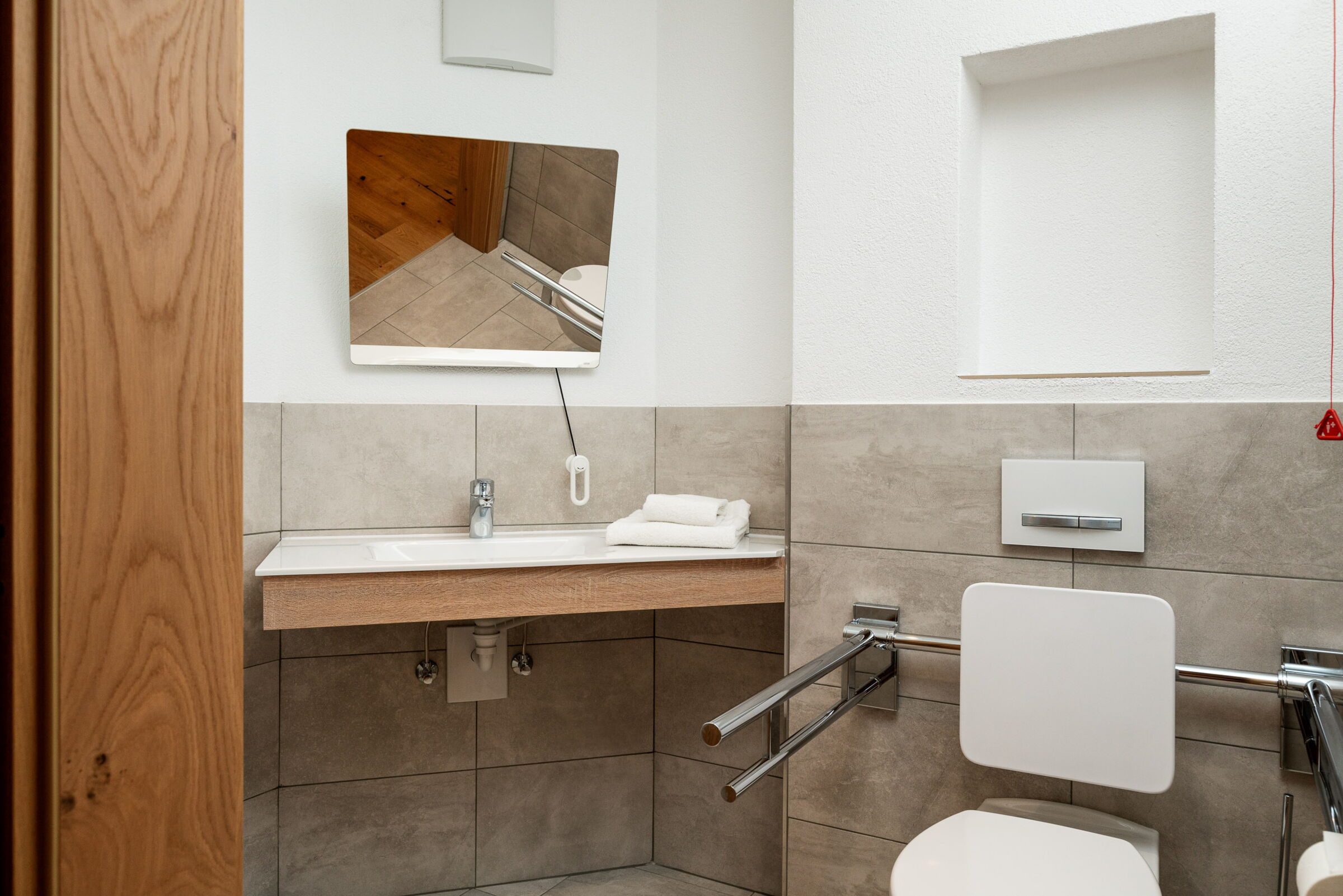 Eine Toilette mit Stützgriffen an beiden Seiten neben dem Waschbecken.
