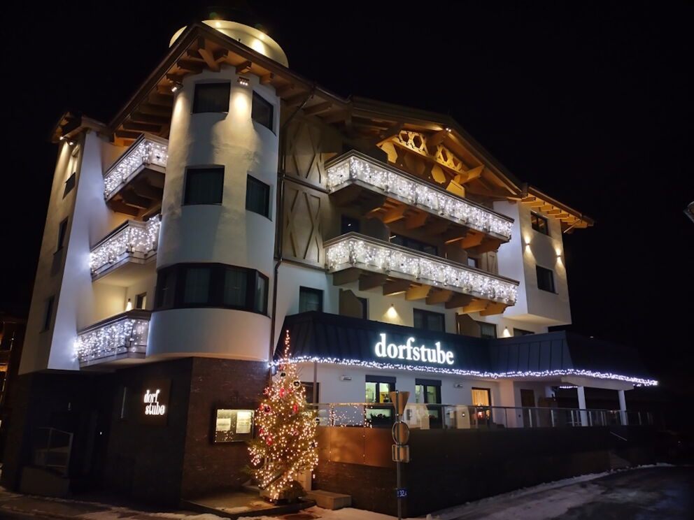 Außenansicht in der Nacht mit schöner LED-Beleuchtung auf der Fasade und den Balkonen mit geschmücktem Weihnachtsbaum.