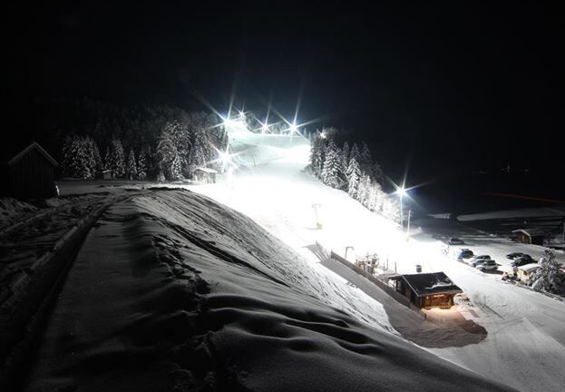 Stanzach-Piste bei Nacht, beleuchtet und schneebedeckt.