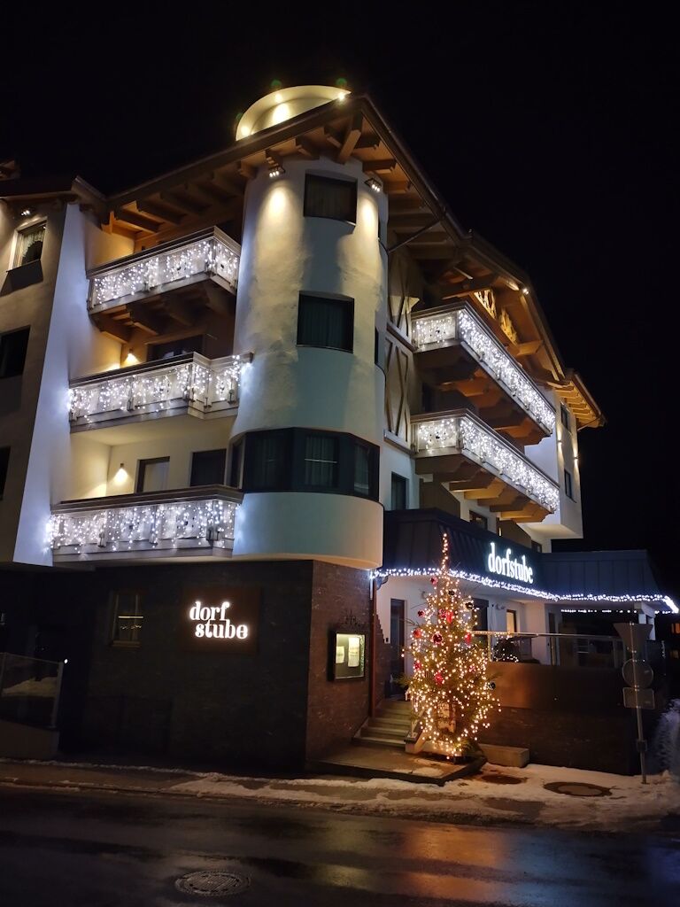 Dorfstube von der Straßenseite in der Nacht mit heller Dekobeleuchtung von Starline-Lichterdekoration.