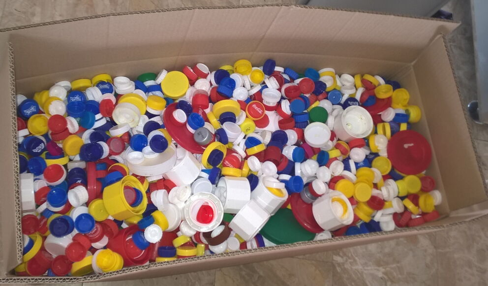 Ein voller Karton mit bunten recyclingfähigen Verschlussdeckeln.