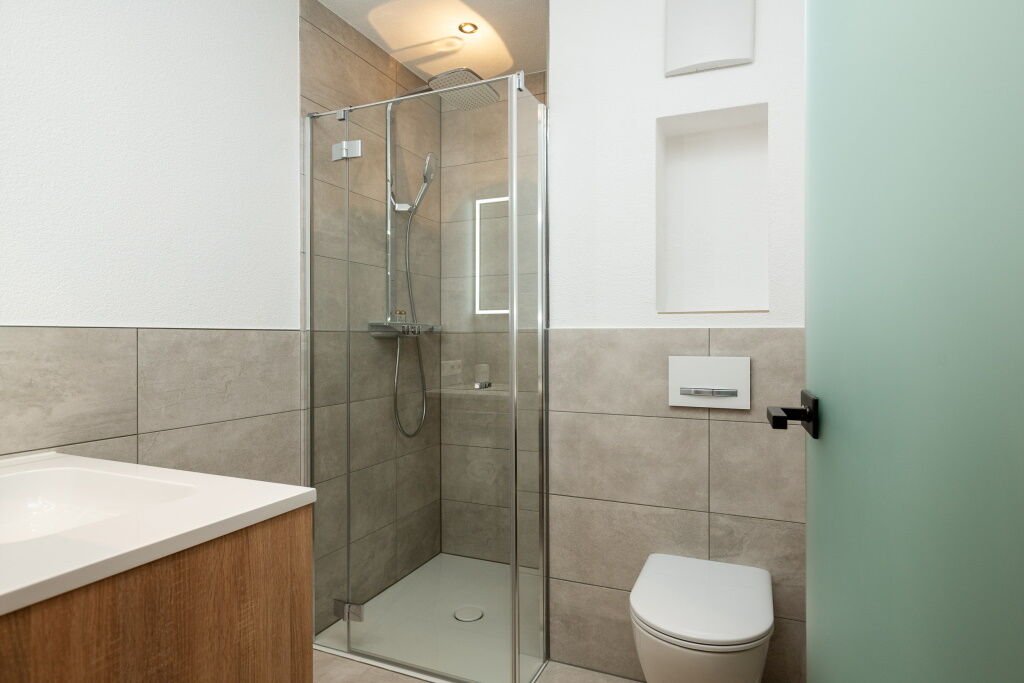 Einzelzimmerbadezimmer mit großer Dusche, Toilette und großem Waschtisch.