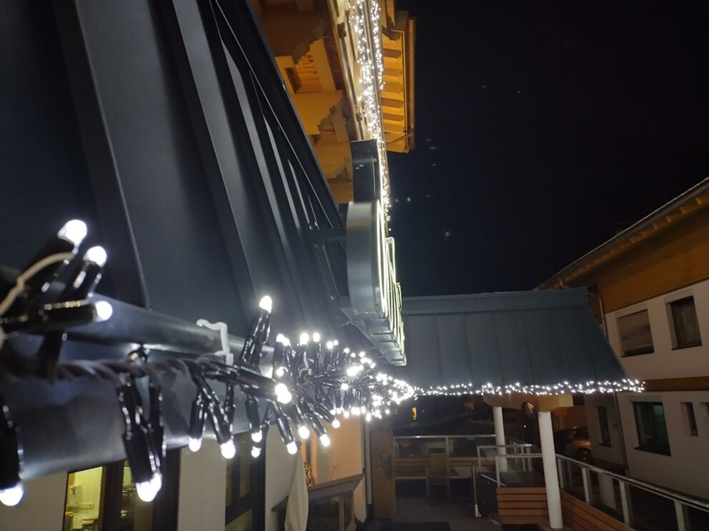 Dekorative Lichterkette mit LED-Strang an der Dachrinne der Dorfstube.