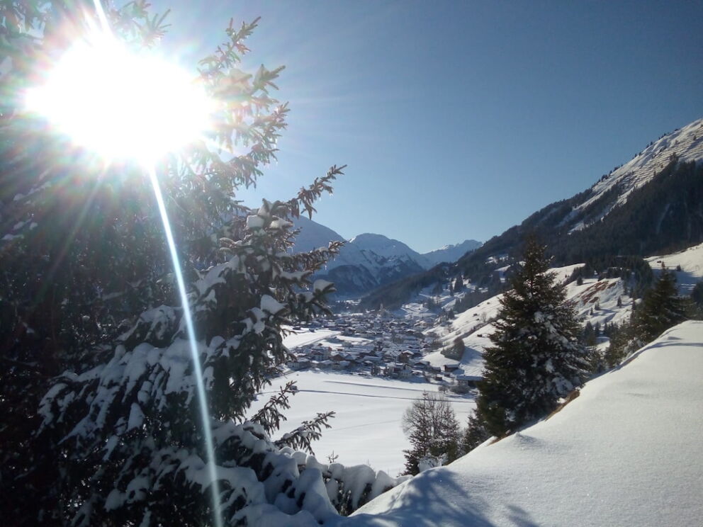 Winterlandschaft im oberen Lechtal bei Holzgau mit verschneiten Wiesen und Sonnenschein.